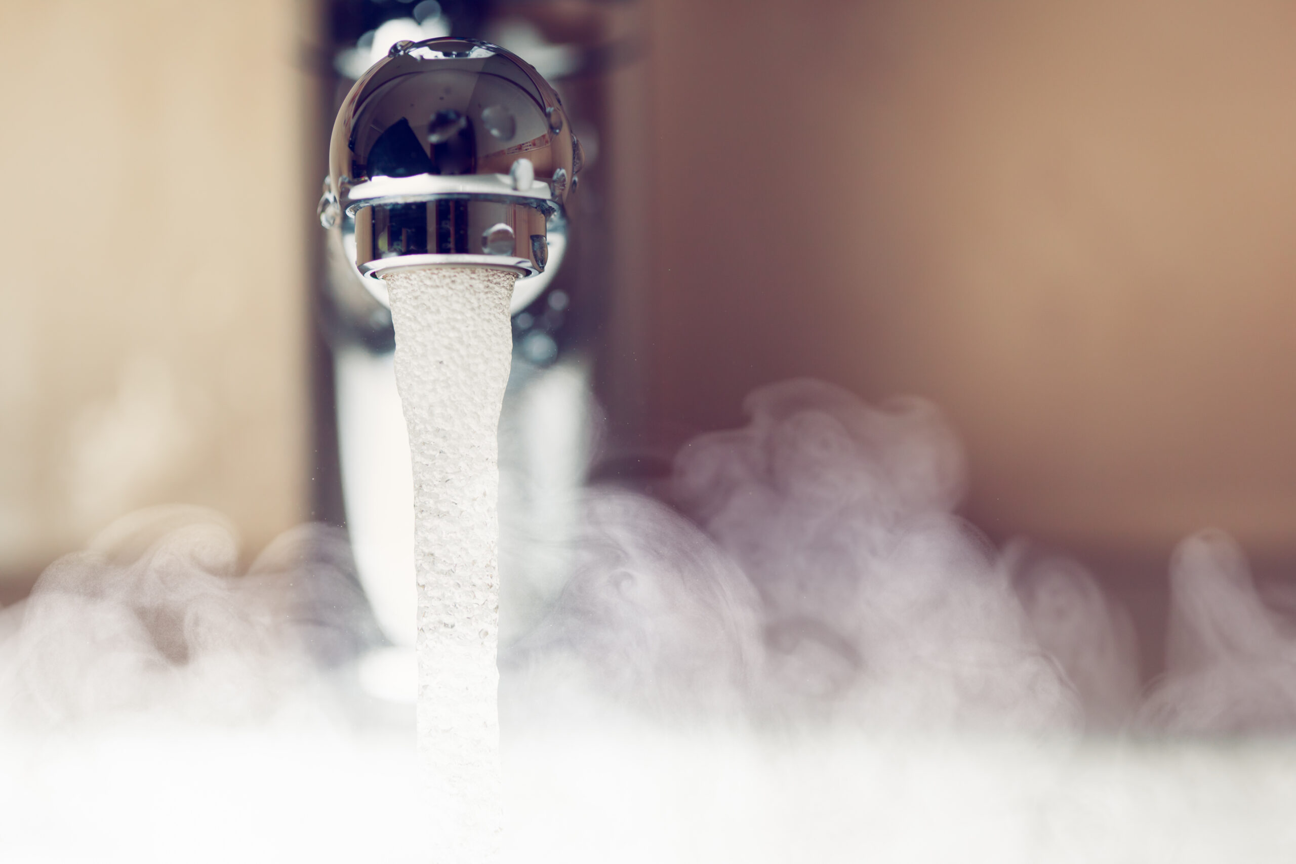 A tap (faucet) with hot water running out and steam escaping